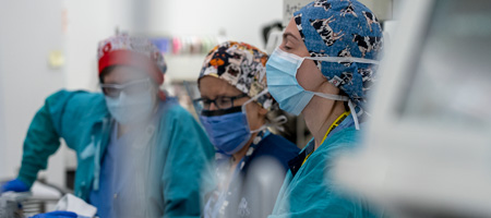 Three medical professionals pushing a gurney. 